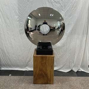 Mirror stainless steel disc sculpture with a central opening on a freestanding base