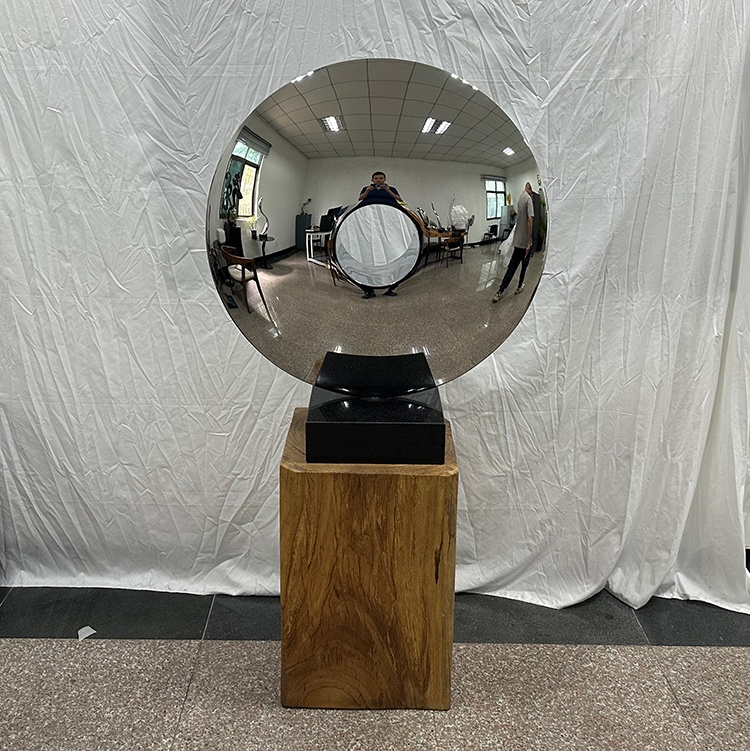 Mirror stainless steel disc sculpture with a central opening on a freestanding base