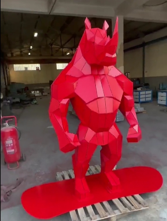 Front view of the same red stainless steel rhino-form sculpture