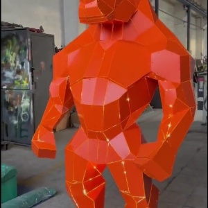 Three-quarter view of the same red angular rhino-form metal sculpture