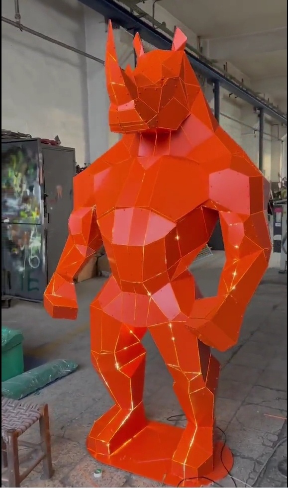Three-quarter view of the same red angular rhino-form metal sculpture