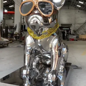 Angled front view of the same mirror-finish dog sculpture showing its seated pose and full base