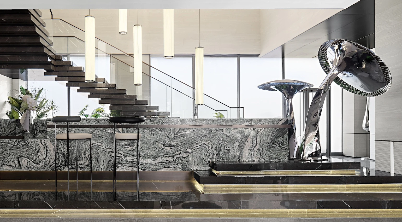 Paired mirror mushroom forms in an interior with stone surfaces, glass balustrades and a staircase