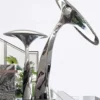 Two mirror-finish mushroom sculptures with upright and curved stems on a shared base.