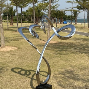 Mirror stainless steel branching ribbon sculpture in a park landscape