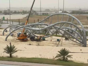 Crane and crew installing a stainless steel landmark sculpture over 30 metres long in Saudi Arabia