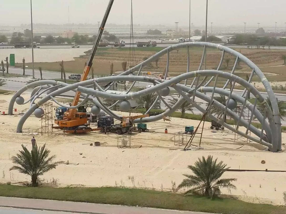 Crane and crew installing a stainless steel landmark sculpture over 30 metres long in Saudi Arabia