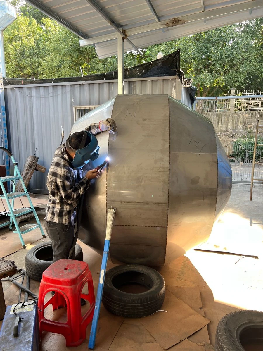 Welder joining formed stainless steel panels of a sphere with continuous full welds