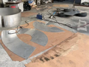 Stainless steel plates cut into curved panels for a large sphere sculpture