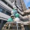 Stacked apple sculpture with reflective and colored surfaces in a landscaped courtyard